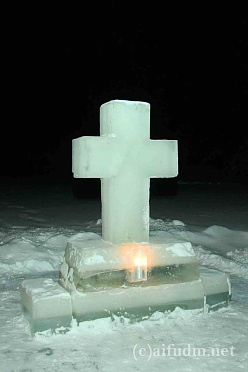 Купель подсвечивается свечами у ледяного креста